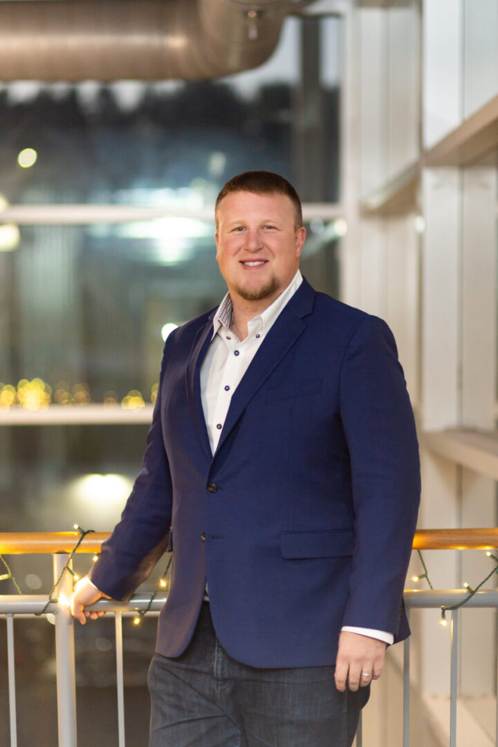 A man in a suit standing next to a railing.